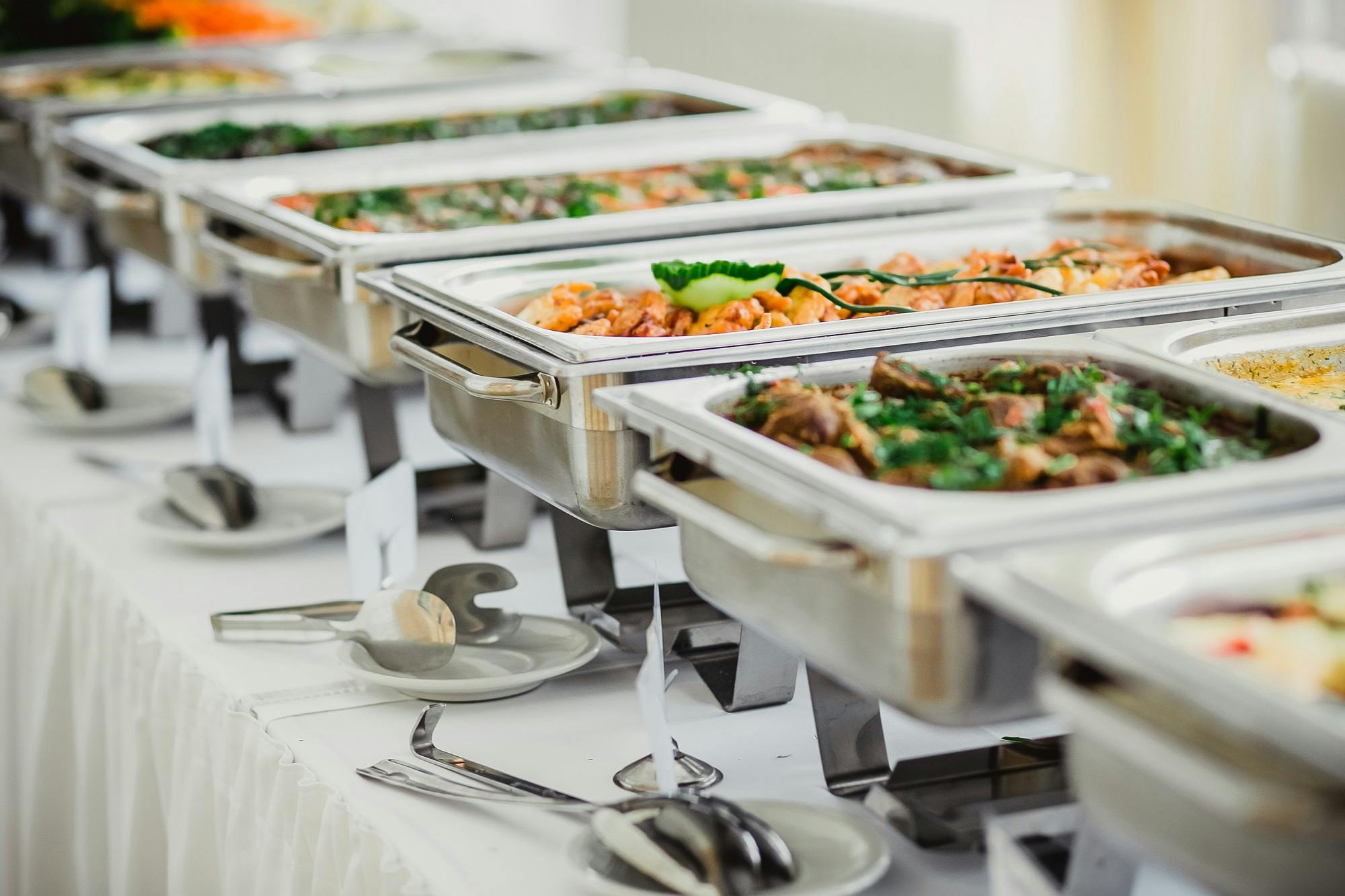 Buffet mit Chafing Dishes voller Speisen für ein Catering-Event.
