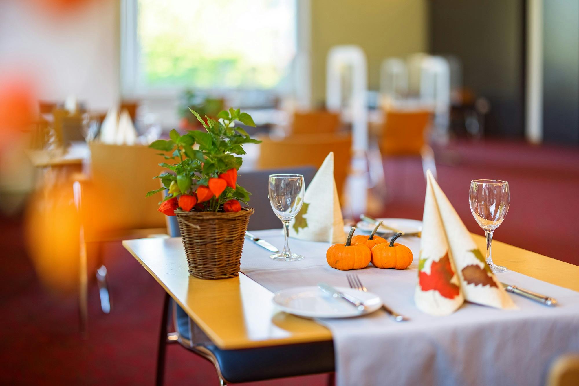 Eleganter Restauranttisch mit Herbstdeko, Servietten und Gläsern.